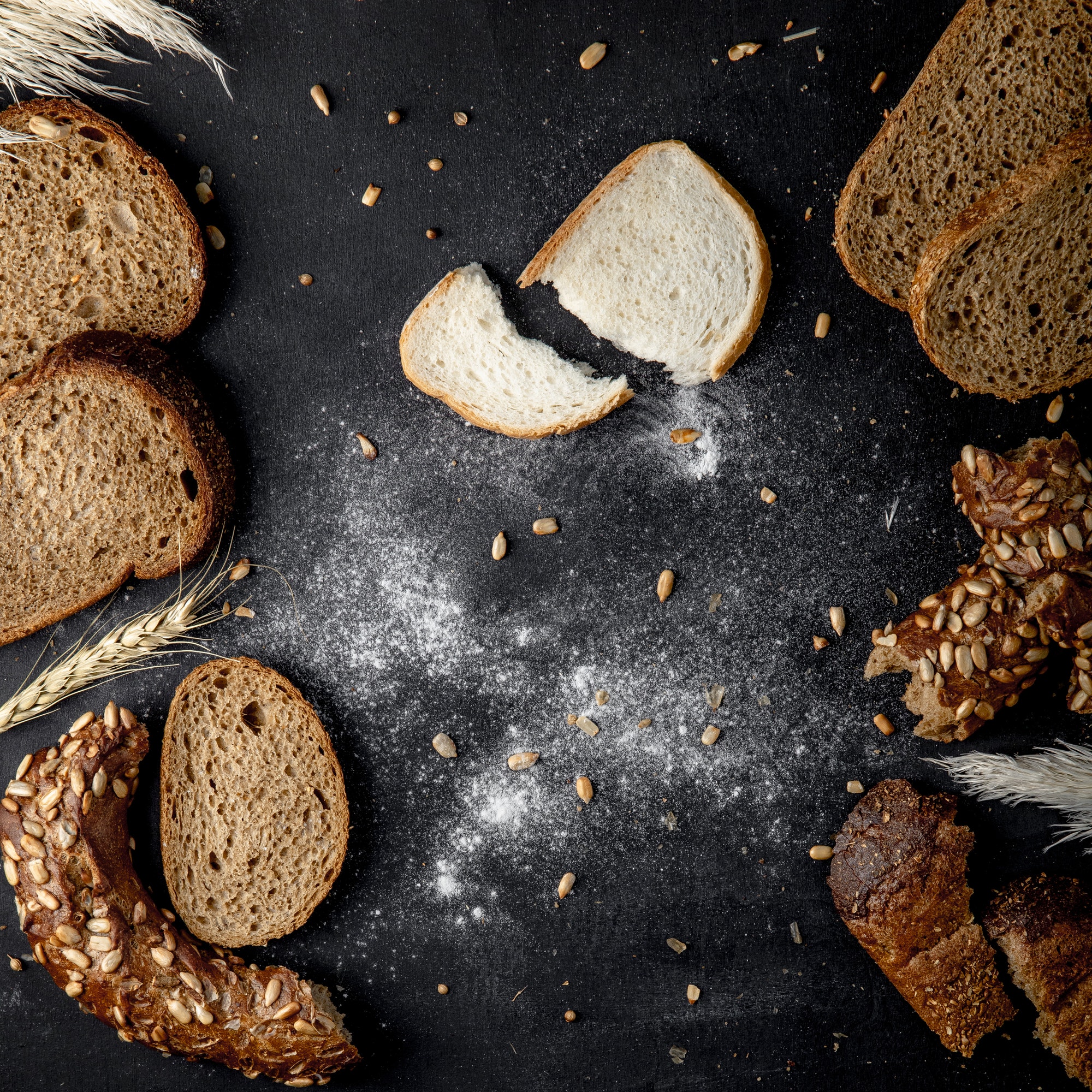 top view of breads as white rye bagel with sunflower seeds and wheat on black background.jpg